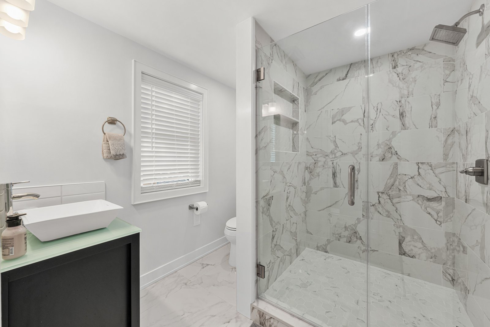 Marble-look porcelain bathroom with tiled shower and hex mosaic pan
